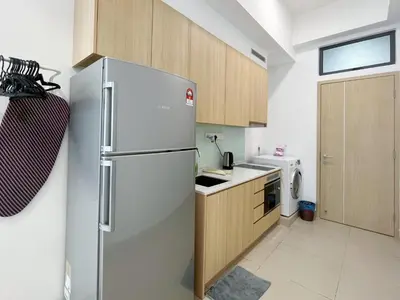 a kitchen with a stainless steel refrigerator and wooden cabinets at The Colony By Infinitum By Paradgm Stay in Kuala Lumpur
