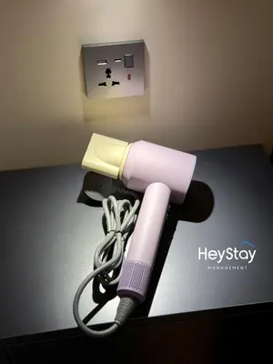 a pink blow dryer on a desk with a chain at Isola KLCC by HeyStay Management in Kuala Lumpur