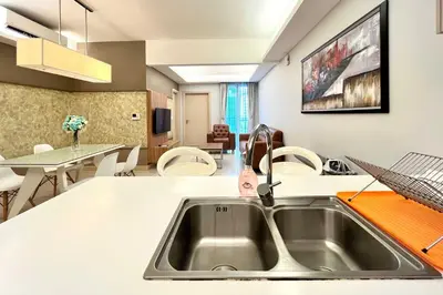 a kitchen with a sink and a living room at High-Floor Suasana KL Stay Cozy & Central in Kuala Lumpur