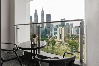 a balcony with a table and chairs and a view of the city at Legasi Residence Direct KLCC VIEW Only10minWalkToKLCC With PS4 AndBoardGames in Kuala Lumpur