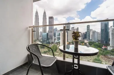 a table and chairs in a balcony with a view of the city at Legasi Residence Direct KLCC VIEW Only10minWalkToKLCC With PS4 AndBoardGames in Kuala Lumpur