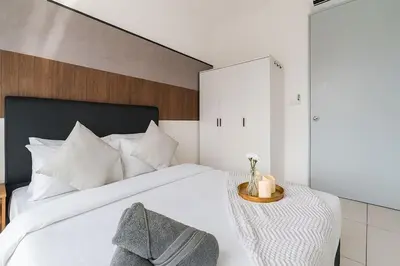 a bedroom with a white bed with a wooden headboard at Kenwingston Platz 15MINS TO KLCC Modern Interior Boardgames A26 in Kuala Lumpur