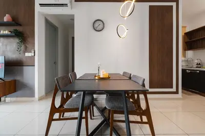 a dining room table with chairs and a clock on the wall at Kenwingston Platz Facing KLCC VIEW 15Mins To KLCC Fit 9Pax A24 in Kuala Lumpur