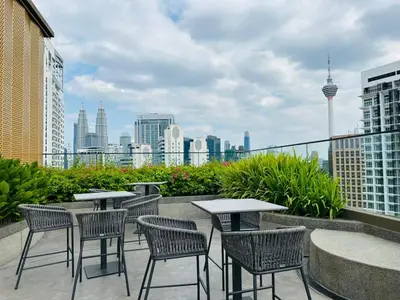 a patio with tables and chairs and a city skyline at Majestic Residence KLCC By MYHOME in Kuala Lumpur