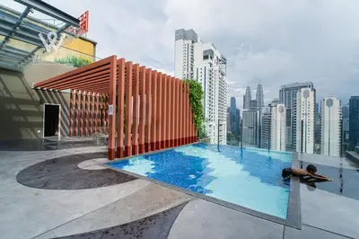 a man laying in a swimming pool on top of a building at Modern & Minimalist Studio at Majestic Residence KL in Kuala Lumpur