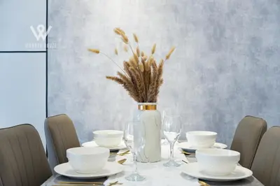 a dining room table with a vase and plates and glasses at Modern & Minimalist Studio at Majestic Residence KL in Kuala Lumpur