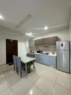a kitchen with a table and a refrigerator at regalia Panorama KLCC view in Kuala Lumpur