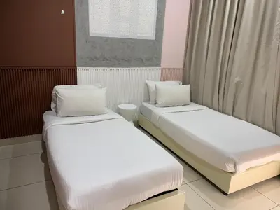 two beds in a room with white sheets and pillows at Homestay at Trion KL in Kuala Lumpur
