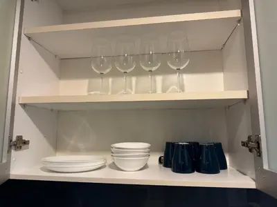 a shelf with wine glasses and plates and bowls at CozyHome Suites Casa Mutiara in Kuala Lumpur