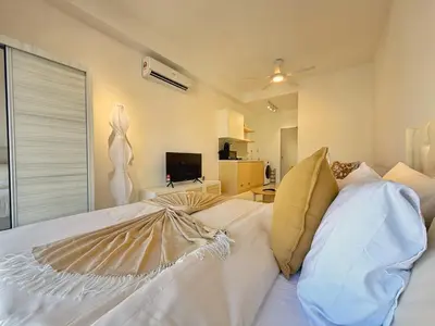 a bedroom with a white bed and a living room at Majestic Charming Studio Suite with Infinity Pool in Kuala Lumpur