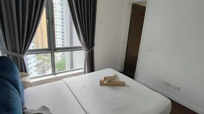 a teddy bear sitting on a bed in front of a window at Pomelo Meet Kuala Lumpur in Kuala Lumpur