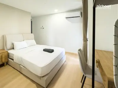 a bedroom with a white bed and a chair at Villa Putra Condo PWTC by Airhost in Kuala Lumpur
