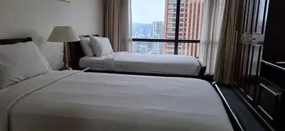 two beds in a hotel room with a large window at Relax Suite Times Square Kl in Kuala Lumpur
