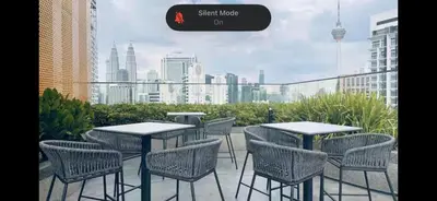 a group of tables and chairs on a balcony with a city skyline at Kampung Marsa at Majestic Residence, Kuala Lumpur in Kuala Lumpur