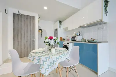 a kitchen with a table with white chairs and blue cabinets at Continew Residensi City Comfort Stay Cozy 1BR 1BA in Kuala Lumpur