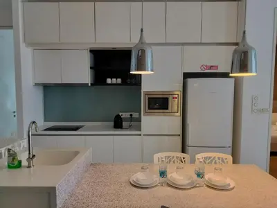 a kitchen with white cabinets and a counter with plates on it at Platinum Klcc by PureStay in Kuala Lumpur