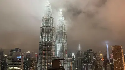 two tall skyscrapers in a city on a foggy day at KL Star Residance KLCC by Nexus 111 in Kuala Lumpur