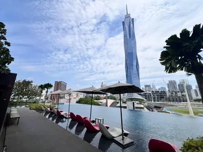 a pool with chairs and umbrellas in front of a building at Opus Residences KL by PILLOWTALKS in Kuala Lumpur