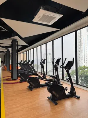 a row of exercise bikes in a gym with windows at Kampung Marsa Retreat, Majestic Residence, KL in Kuala Lumpur