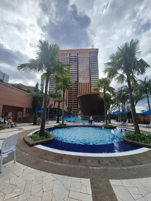 a large pool with palm trees and a building at KL Residences at Berjaya Times Square in Kuala Lumpur