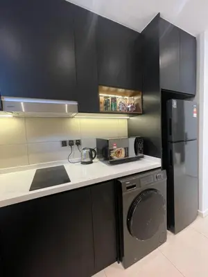 a kitchen with black cabinets and a washer and a refrigerator at KL Nice Condo in Kuala Lumpur