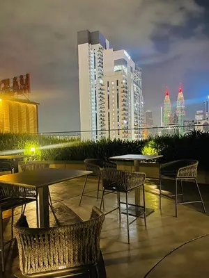 a patio with tables and chairs with a city skyline at Majestic Residence Klcc by Apple in Kuala Lumpur