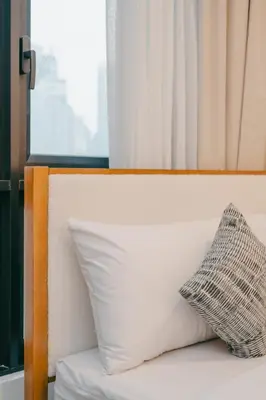 a pillow sitting on top of a bed with a window at Cozy Minimalist Studio KL, Agile Residence Bukit Bintang in Kuala Lumpur
