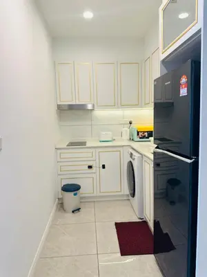 a kitchen with white cabinets and a black refrigerator at Supper Suite By Axon Residence in Kuala Lumpur