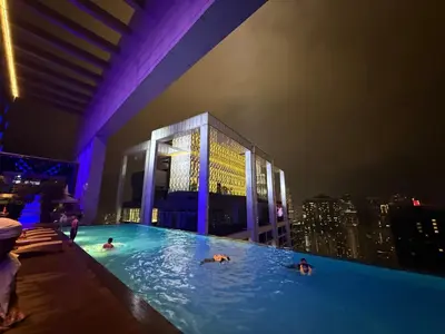 a group of people swimming in a swimming pool at night at Platinum Klcc by StayAura in Kuala Lumpur