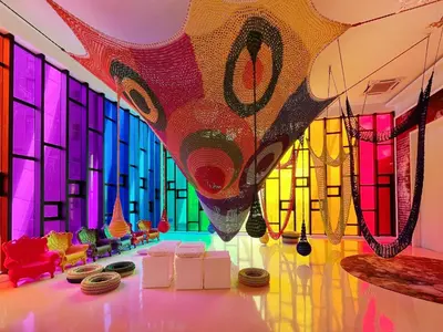 a room with colorful windows and tables and chairs at Arte Mont Kiara by whitedoorz Apartment in Kuala Lumpur