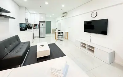 a living room with a couch and a tv on a wall at Summer Suites KLCC Vibes in Kuala Lumpur