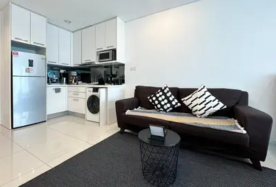 a living room with a couch and a kitchen at Summer Suites KLCC Vibes in Kuala Lumpur