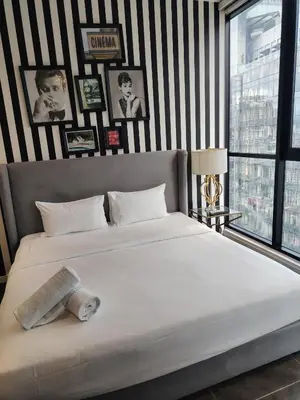 a bedroom with a large white bed with black and white stripes at Scarletz Suites KLCC Twin Tower by Skyview in Kuala Lumpur