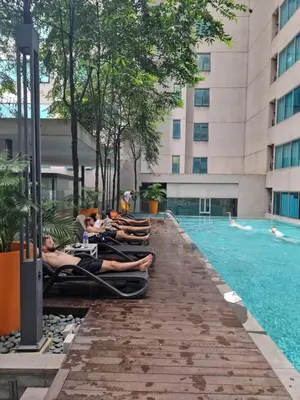 a group of people laying on the side of a swimming pool at Summer suites klcc 5 min walk by AA Global in Kuala Lumpur