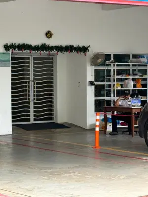 a man sitting at a table in front of a garage at Happy Homes Kuala Lumpur Rooms in Kuala Lumpur