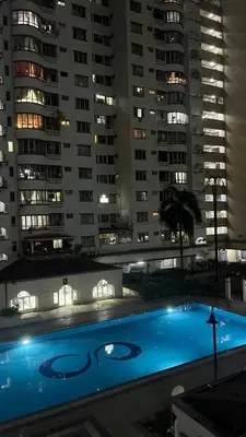 a swimming pool in front of tall buildings at night at Homestay in Kuala Lumpur