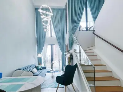 a living room with a staircase and blue curtains at The Colony Infinitum by Manila in Kuala Lumpur