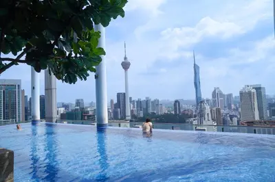a man standing in a infinity pool overlooking a city at The Colony Infinitum by Manila in Kuala Lumpur
