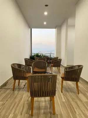 a group of chairs and tables in a room with a window at The Colony by Klcc Wisma Infinitum in Kuala Lumpur
