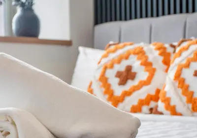 a bed with orange and white pillows on it at Riveria Sky Residences KL Sentral with Infinity Pool in Kuala Lumpur