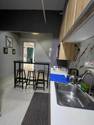 a kitchen with a sink and a table with stools at Nour Homestay KLCC View - COZY 1 in Kuala Lumpur