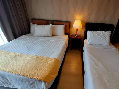 two beds in a hotel room next to a lamp at Time square luxury suites in Kuala Lumpur