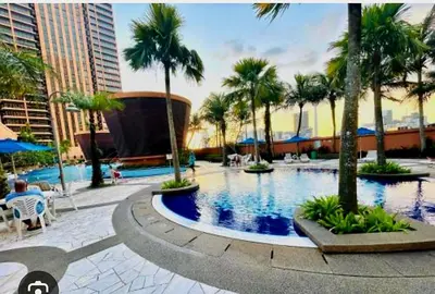 a large swimming pool with palm trees in a city at Time square luxury suites in Kuala Lumpur