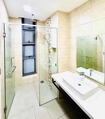 a bathroom with a sink and a glass shower at Robertson Residence by Aspire Suites in Kuala Lumpur
