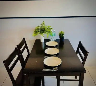 a black table with four chairs and plates on it at Robertson Residence by Aspire Suites in Kuala Lumpur