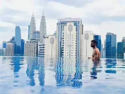a man in a infinity pool with a city skyline at Home For Traveler At Majestic Residence in Kuala Lumpur