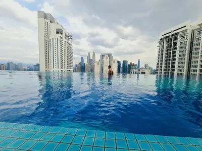 a man in a infinity pool on the roof of a city at Home For Traveler At Majestic Residence in Kuala Lumpur
