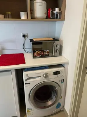 a kitchen with a microwave and a washing machine at Arte Plus Homestay Condo in Kuala Lumpur