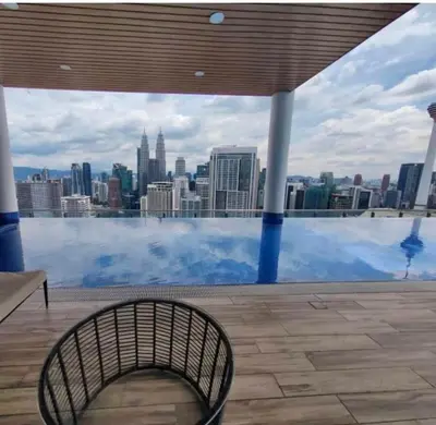 a bench in front of a pool with a view of a city at The Colony By Feel Home in Kuala Lumpur