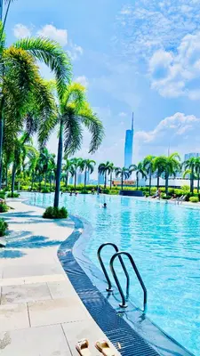 a swimming pool with palm trees in a city at Trion KL Family Residences in Kuala Lumpur